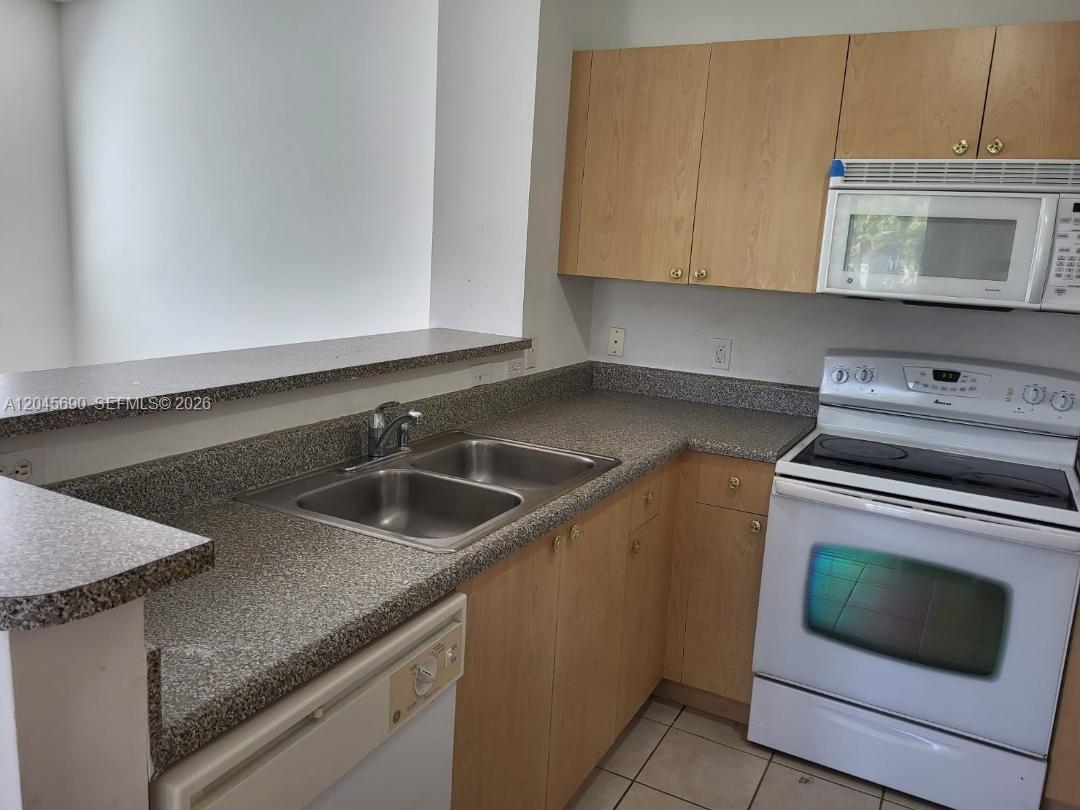 8070 North Nob Hill Road, Unit 208 Tamarac, FL 33321 - Photo 5 of 16 a kitchen with granite countertop a sink stove and microwave