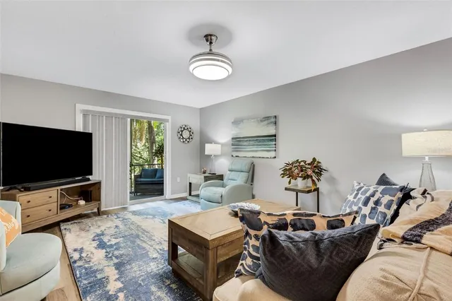 a living room with furniture a flat screen tv and a large window