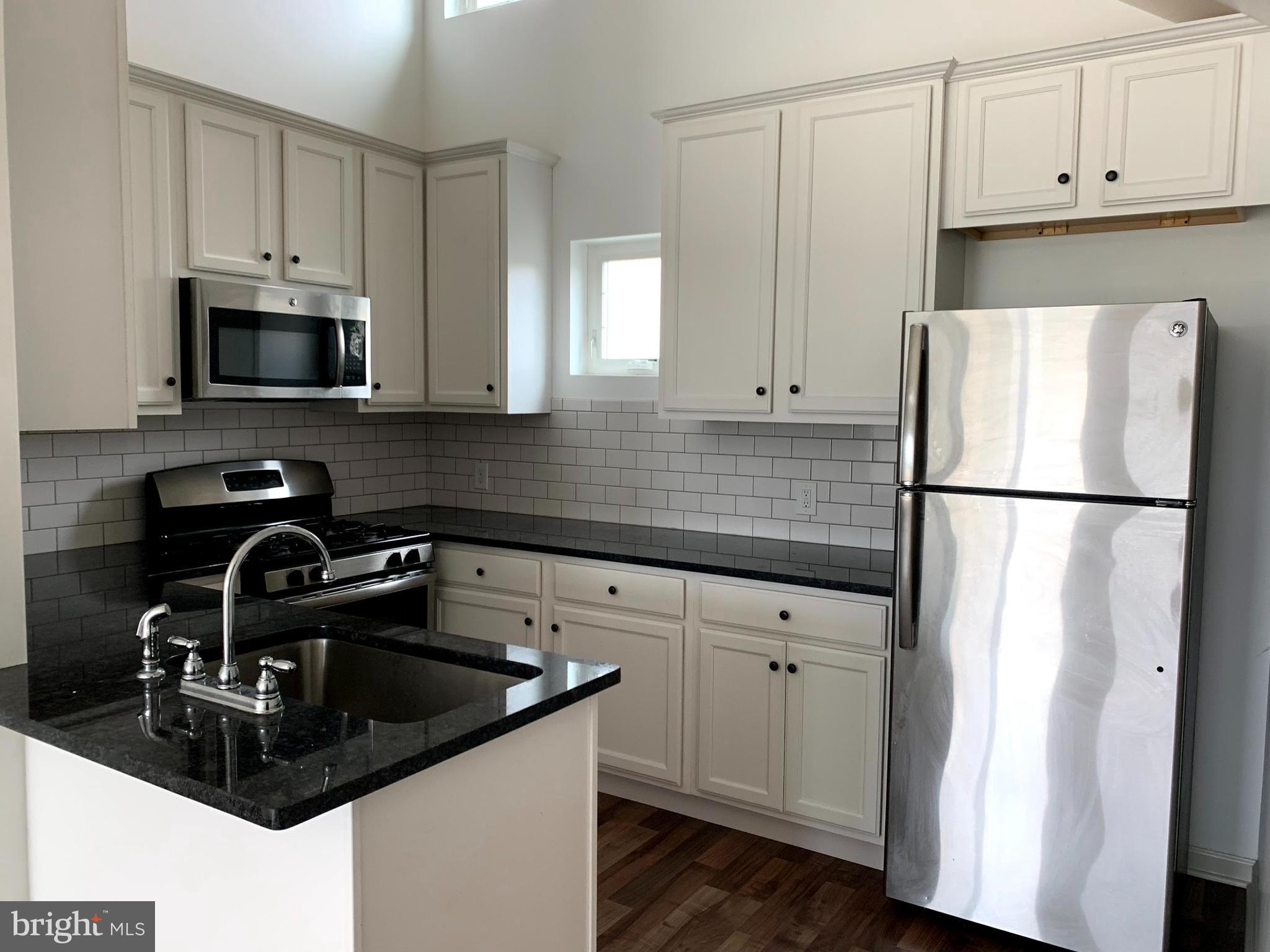 5261 Ridge Avenue, Unit 305 Philadelphia, PA 19128 - Photo 1 of 7 a kitchen with white cabinets a sink and white appliances