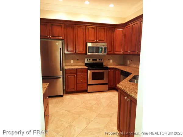 a kitchen with stainless steel appliances granite countertop a refrigerator a stove and a sink with wooden cabinets
