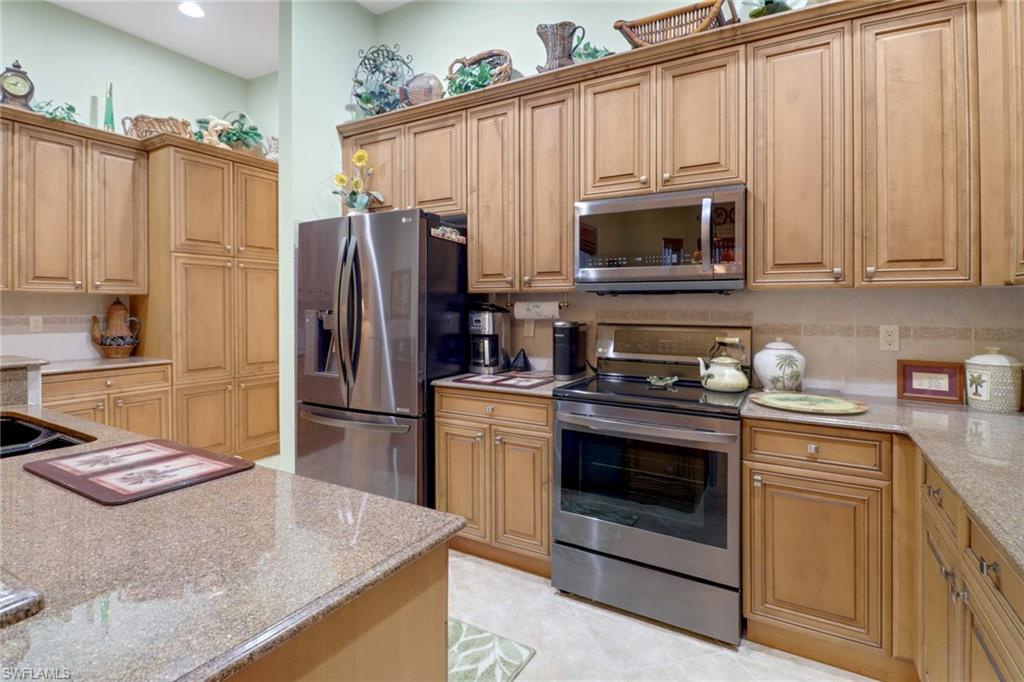 20531 Foxworth Circle Estero, FL 33928 - Photo 11 of 50 Kitchen with appliances with stainless steel finishes, light stone counters, and light tile patterned floors