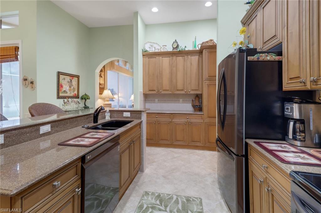 20531 Foxworth Circle Estero, FL 33928 - Photo 10 of 50 Kitchen featuring backsplash, sink, light stone counters, light tile patterned floors, and black appliances