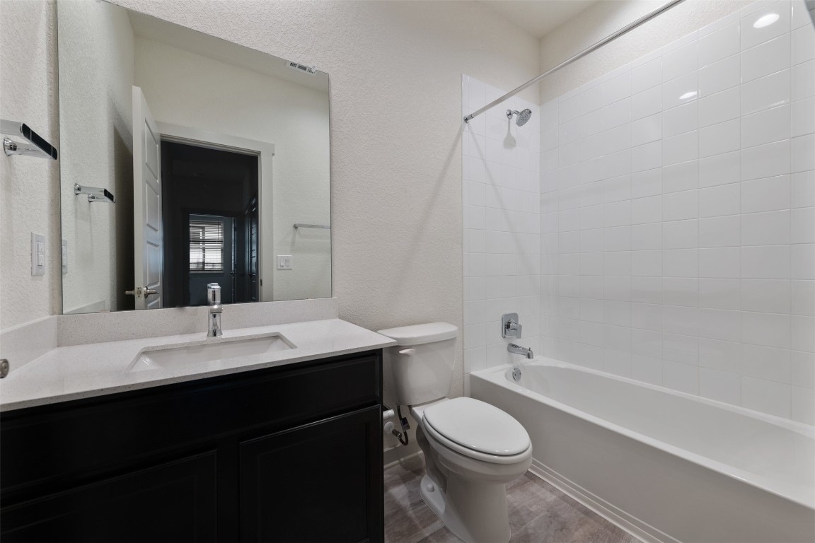220 Deserti Road Leander, TX 78641 - Photo 14 of 16 Bathroom with vanity, shower / tub combination, wood finished floors, and a textured wall