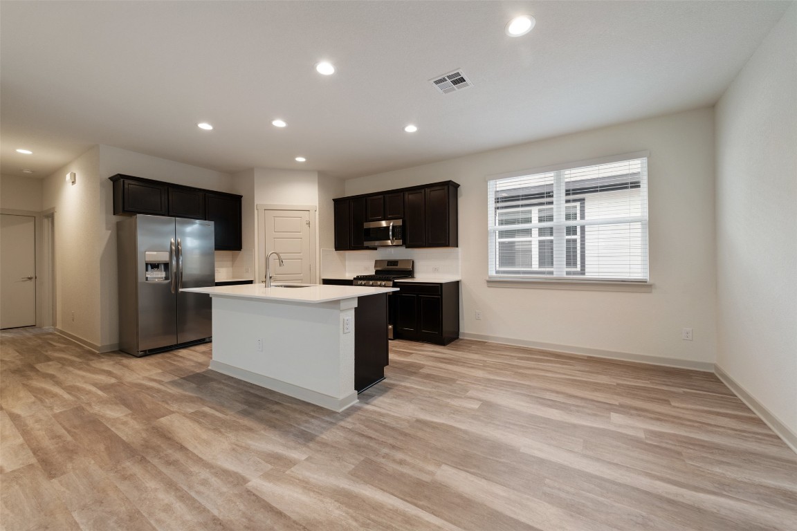 220 Deserti Road Leander, TX 78641 - Photo 6 of 16 Kitchen with appliances with stainless steel finishes, recessed lighting, light countertops, light wood finished floors, and a center island with sink