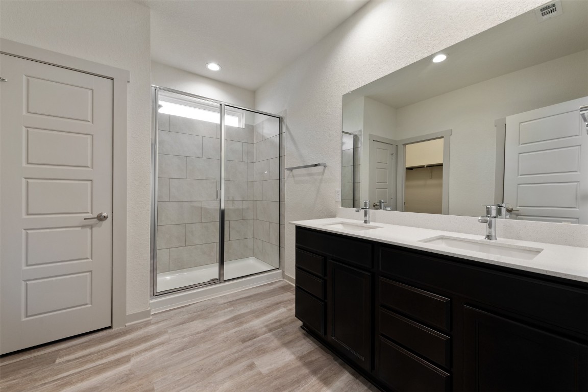 220 Deserti Road Leander, TX 78641 - Photo 10 of 16 Bathroom with a shower stall, double vanity, wood finished floors, a spacious closet, and recessed lighting
