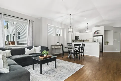 a living room with furniture wooden floor and a kitchen view