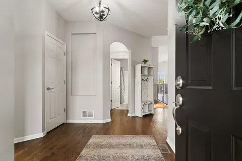 a view of a hallway with wooden floor and a chandelier