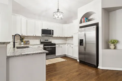 a kitchen with stainless steel appliances granite countertop a refrigerator a stove a sink and a microwave