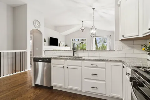 a kitchen with stainless steel appliances granite countertop a sink a stove and a wooden floors