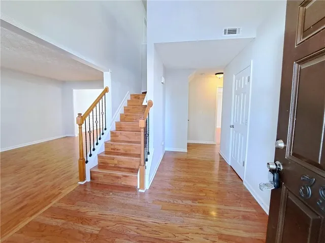 a view of a hallway with wooden floor and staircase