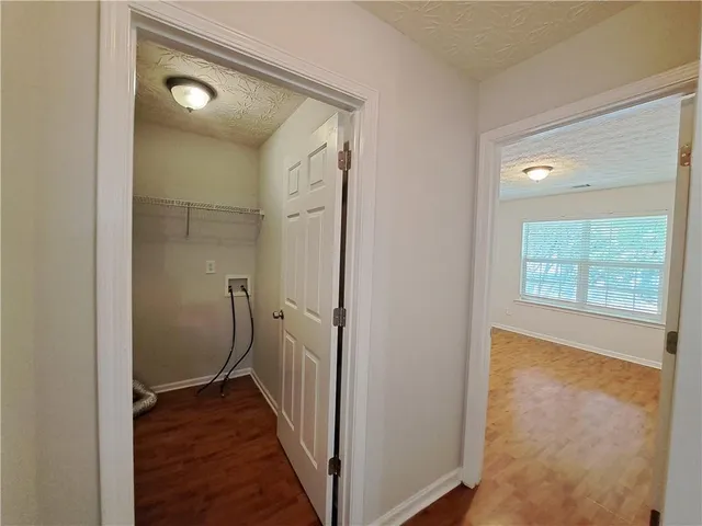 a view of a hallway with wooden floor and a bathroom
