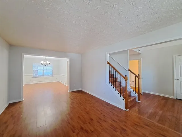 a view of an empty room with wooden floor and stairs