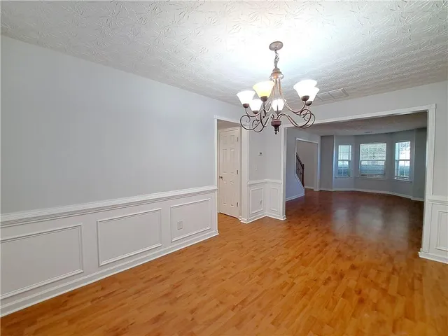 a view of a livingroom with a chandelier fan and wooden floor