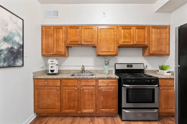 a kitchen with granite countertop a stove a sink and wooden cabinets