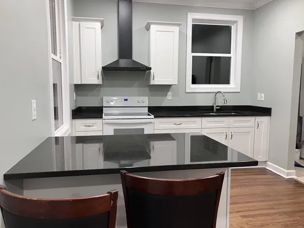 a kitchen with granite countertop a sink a stove and cabinets