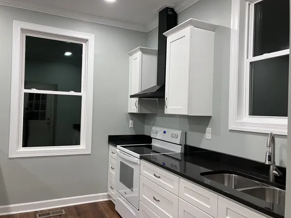 a kitchen with granite countertop white cabinets and black appliances