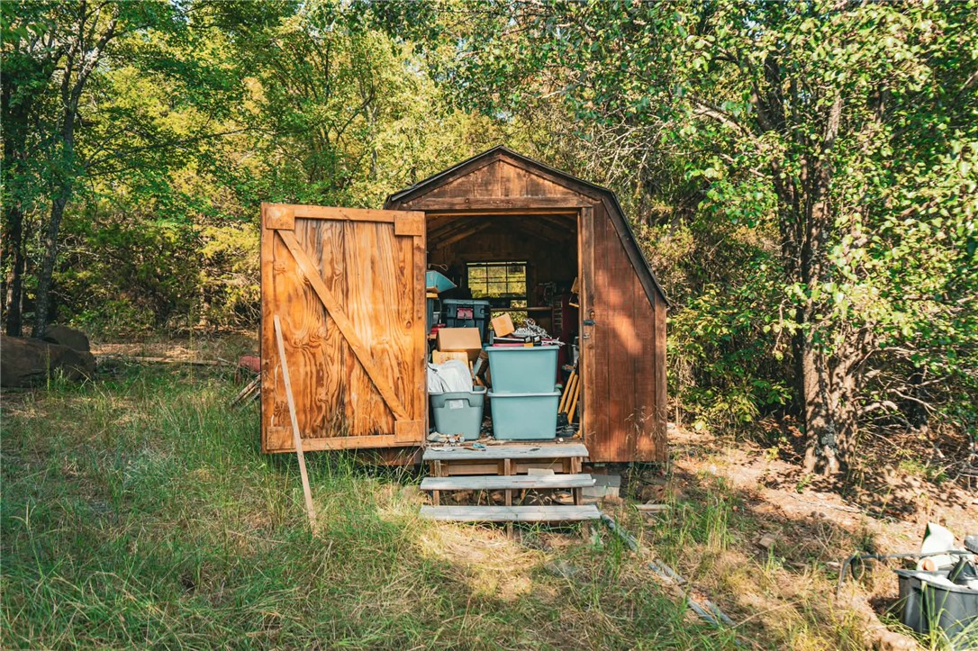 1014 Excelsior Road Greenwood, AR 72936 - Photo 26 of 37 Wood-sided storage shed with a gambrel roof and a single wood door