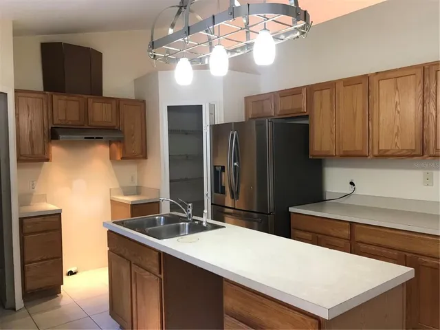 a kitchen with stainless steel appliances a sink a refrigerator a counter space and cabinets