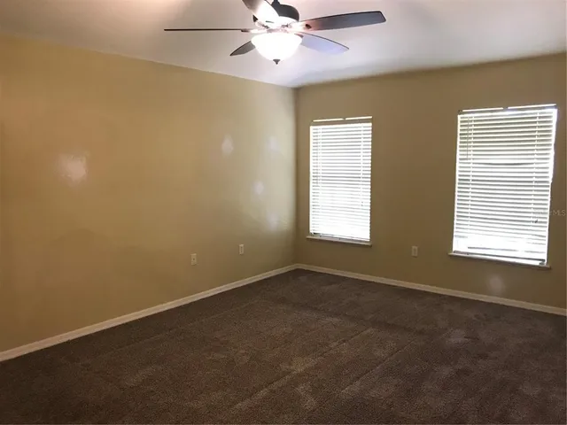 an empty room with windows and fan