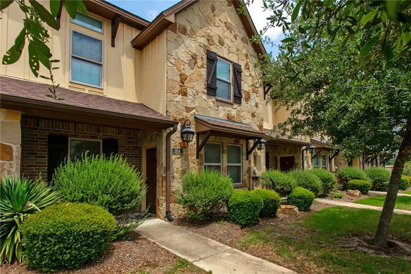 a view of a house with brick walls and a yard with plants