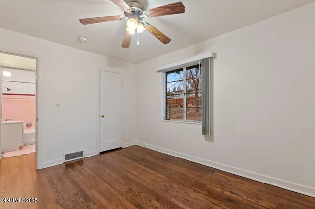 an empty room with wooden floor chandelier fan and windows
