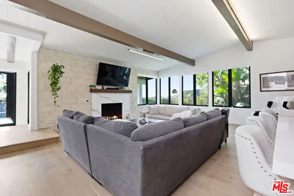 a living room with furniture large windows and a fireplace