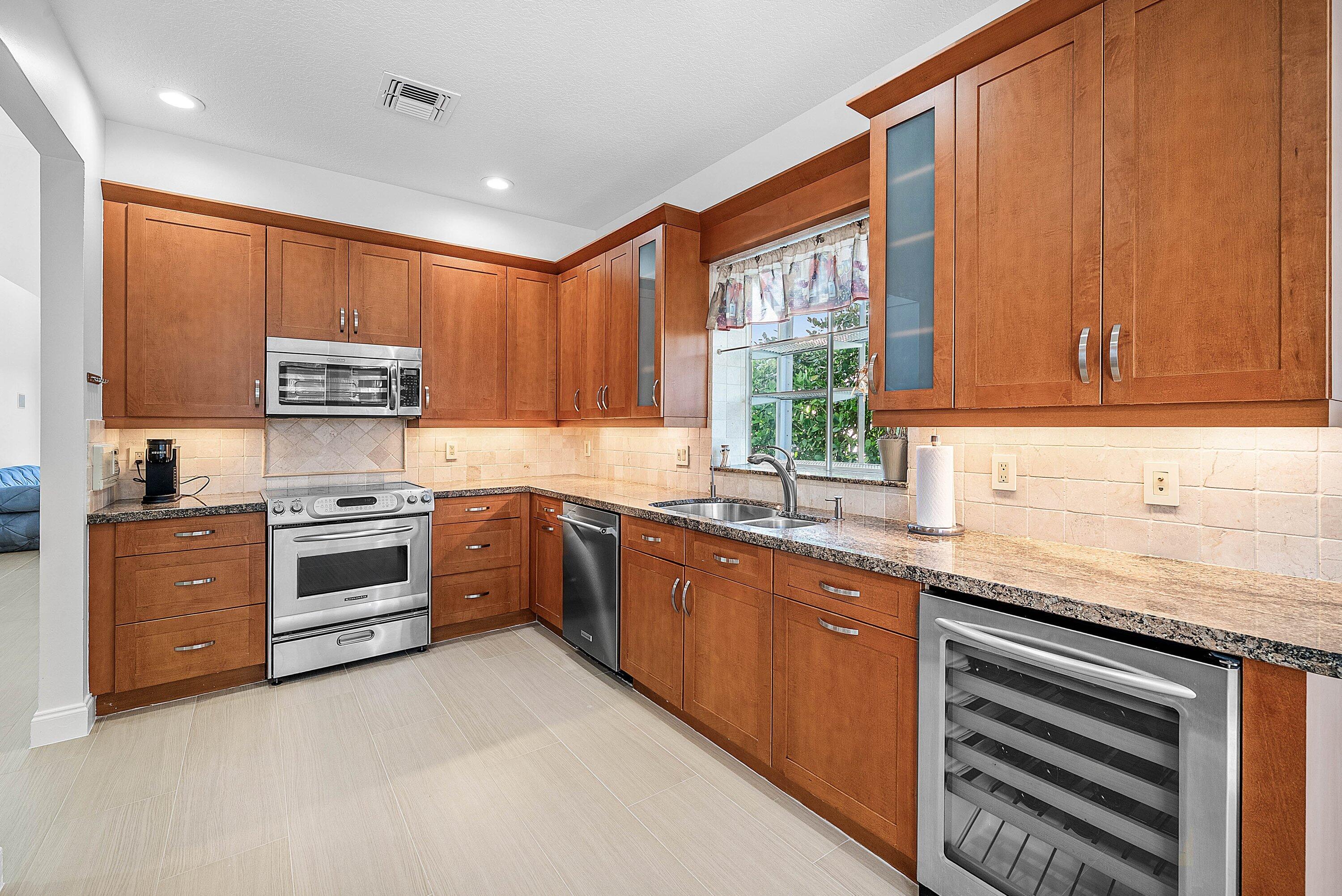 5855 Northwest 42nd Way Boca Raton, FL 33496 - Photo 17 of 77 a kitchen with stainless steel appliances granite countertop a stove a sink and a microwave