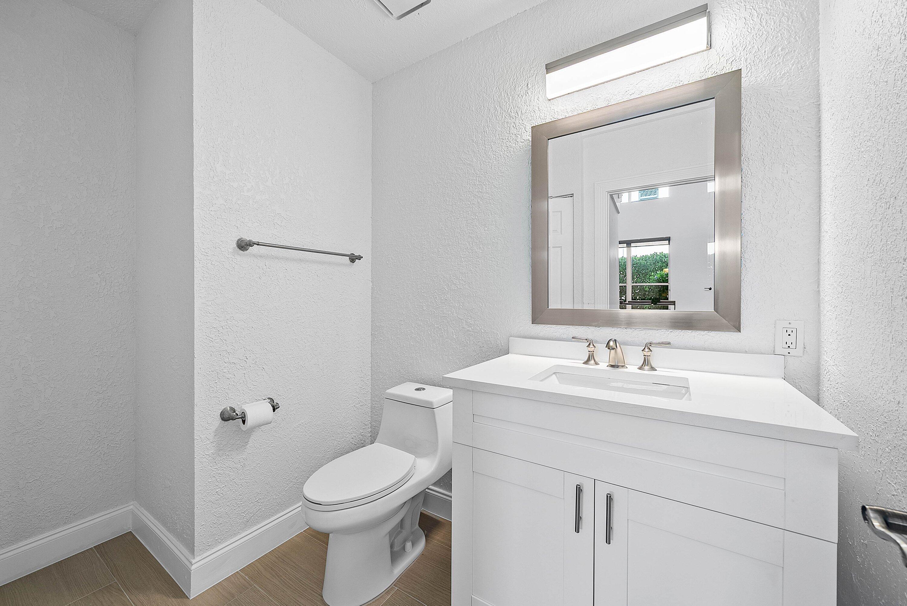 5855 Northwest 42nd Way Boca Raton, FL 33496 - Photo 22 of 77 a bathroom with a toilet a sink a mirror and vanity