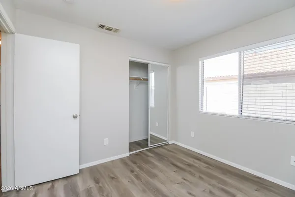 an empty room with wooden floor and windows