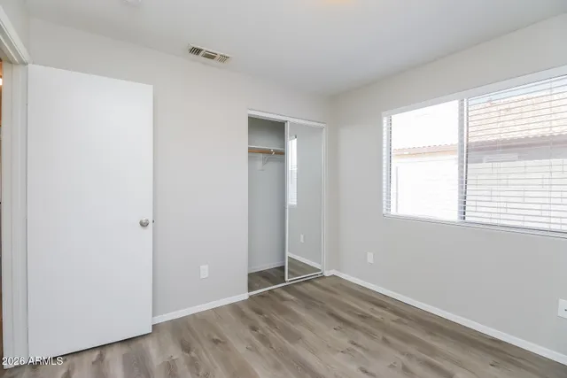 an empty room with wooden floor and windows