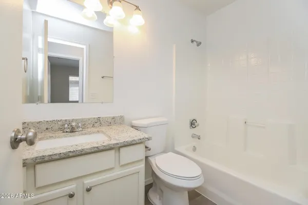 a bathroom with a granite countertop sink a toilet and a mirror
