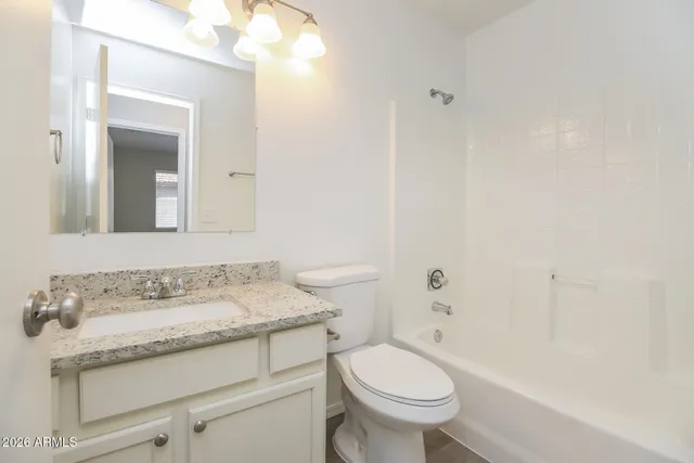 a bathroom with a granite countertop sink a toilet and a mirror