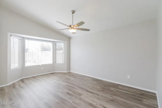 an empty room with wooden floor fan and windows