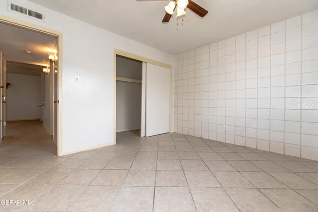 a view of an empty room with a chandelier fan