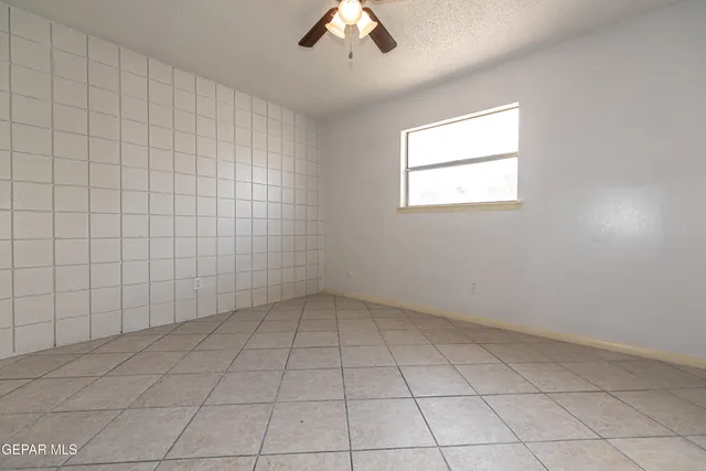 an empty room with a ceiling fan and window