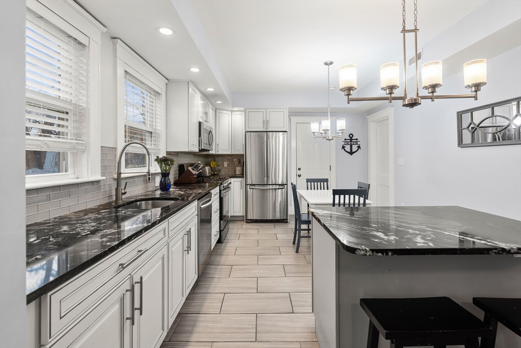 51 New Ocean Street, Unit 2 Swampscott, MA 01907 - Photo 7 of 20 a kitchen with kitchen island granite countertop a sink stove and cabinets