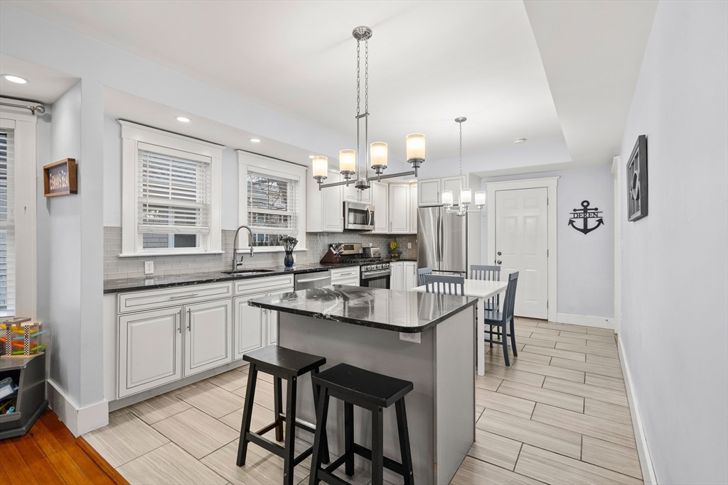 51 New Ocean Street, Unit 2 Swampscott, MA 01907 - Photo 8 of 20 a kitchen with kitchen island a dining table chairs sink and cabinets