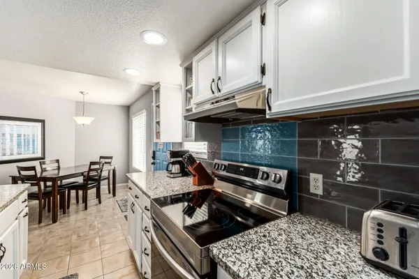 a kitchen with stainless steel appliances granite countertop a stove a sink and a dining table