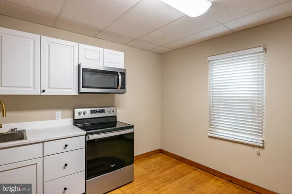 a kitchen with granite countertop white cabinets appliances and a window