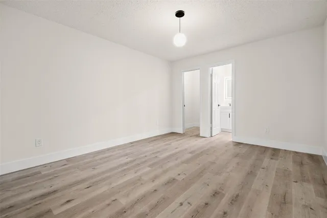a view of an empty room with wooden floor ceiling fan and windows