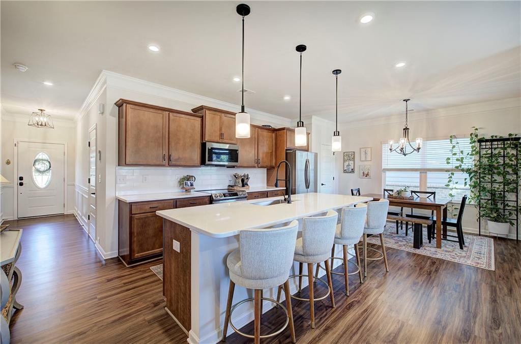402 Perth Drive Cartersville, GA 30121 - Photo 6 of 31 a open kitchen with stainless steel appliances granite countertop a stove a refrigerator a kitchen island a dining table and chairs with wooden floor