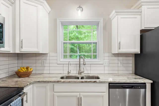 a kitchen with stainless steel appliances granite countertop a sink a stove and a white wooden cabinets
