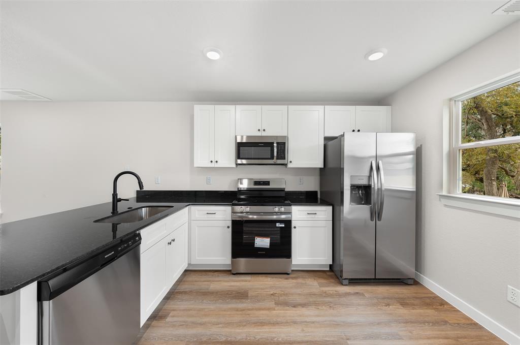 1536 Alexander Avenue, Unit A & B Waco, TX 76708 - Photo 16 of 31 The kitchen features white cabinetry, stainless steel appliances, dark countertops, and wood-look flooring