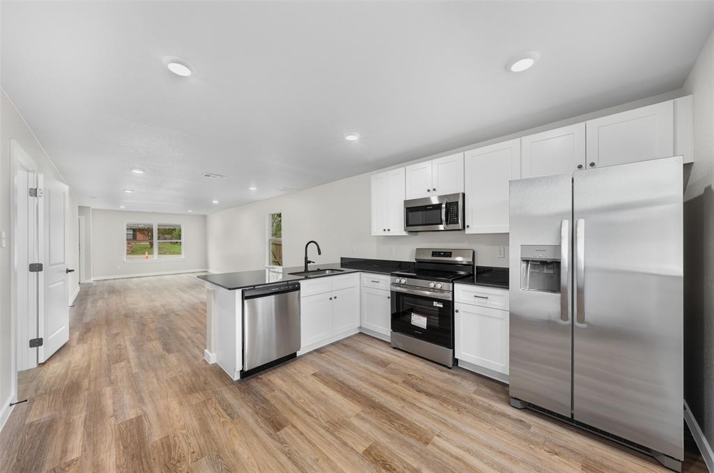 1536 Alexander Avenue, Unit A & B Waco, TX 76708 - Photo 17 of 31 Open-concept kitchen and living area featuring wood-look flooring, white cabinetry, stainless steel appliances, and recessed lighting
