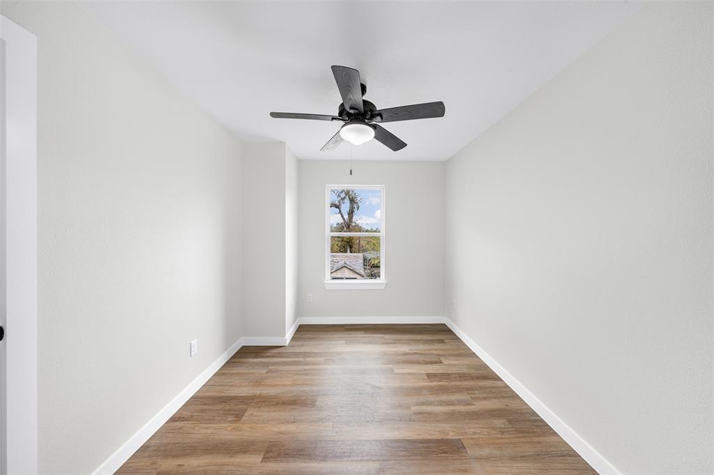 1536 Alexander Avenue, Unit A & B Waco, TX 76708 - Photo 24 of 31 This room features wood plank flooring, light-colored walls, a window with a view of trees, and a ceiling fan with an integrated light fixture