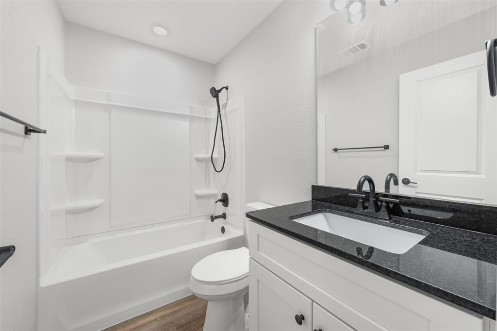 1536 Alexander Avenue, Unit A & B Waco, TX 76708 - Photo 26 of 31 Bathroom featuring a vanity with a dark countertop and white sink, a mirror, and a bathtub with an integrated shower