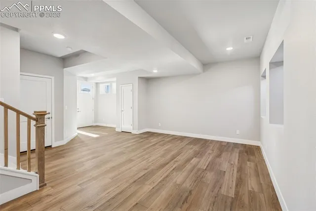 a view of an empty room with wooden floor and stairs
