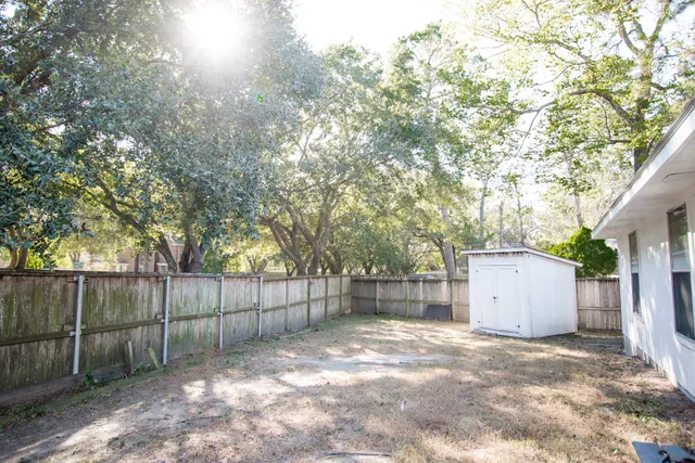 a backyard of a house with a tree and wooden fence