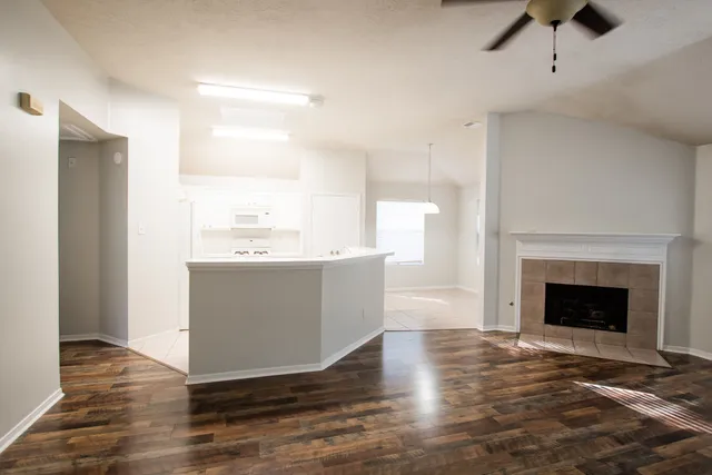 a living room with a fireplace wooden floor and ceiling fan