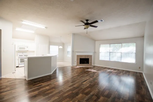 a view of an empty room with a kitchen and a window